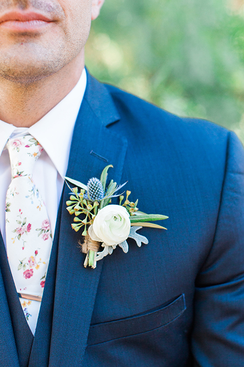 California outdoor wedding at the rancho san antonio groom navy notch lapel suit with a matching vest and white dress shirt with a long white and pink floral tie with a white floral boutonniere close up