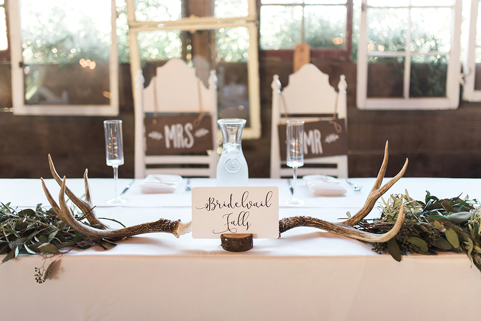 California outdoor wedding at the rancho san antonio reception decor white sweetheart table with animal decor and white chairs with brown wood mr and mrs signs with white place settings and table number wedding photo idea for reception