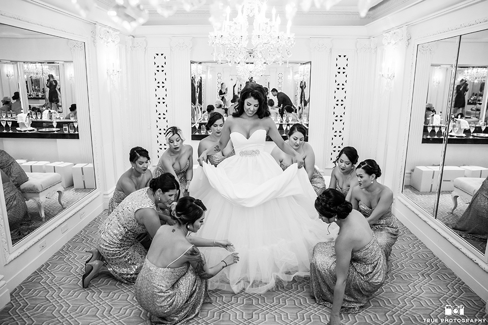 San diego glamorous wedding at the us grant hotel bride strapless ball gown with a tulle skirt and sweetheart neckline and a crystal belt with a long veil holding white floral bridal bouquet with bridesmaids getting ready gold dresses black and white photo