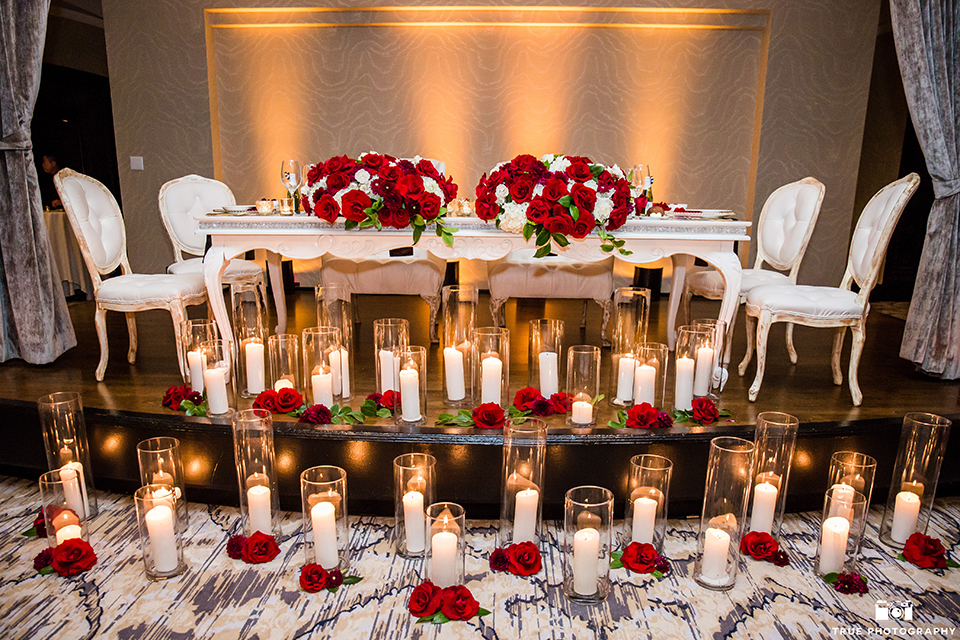San diego glamorous wedding at the us grant hotel wedding reception decor white vintage sweetheart table and red and white flower centerpiece decor with tall white candles in glass vases on floor wedding photo idea for sweetheart table
