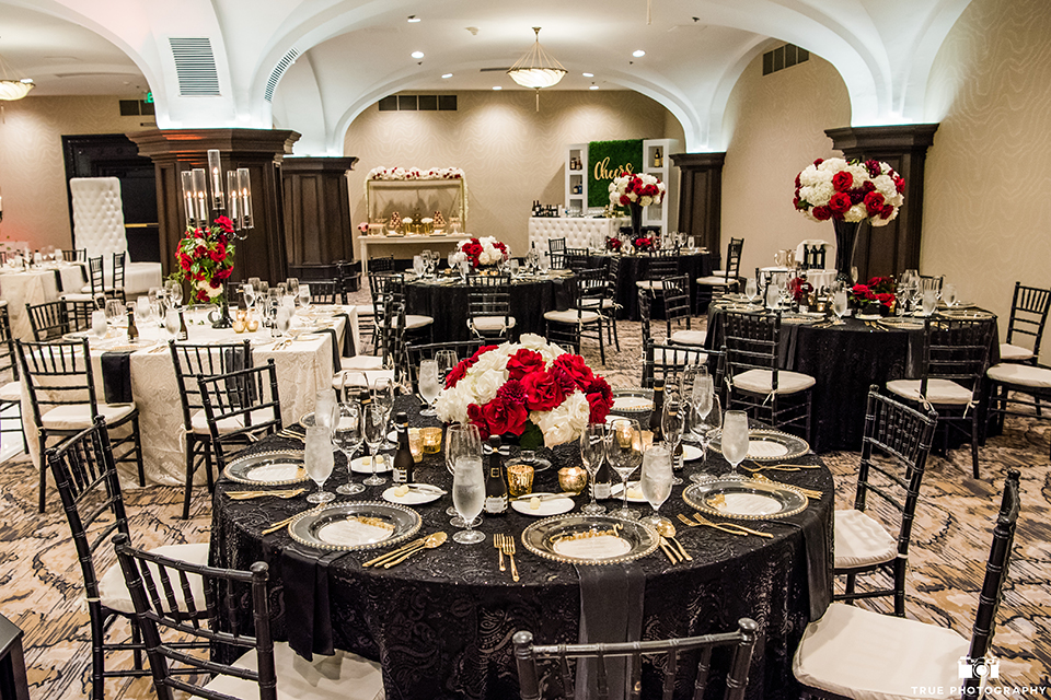 San diego wedding at the us grant hotel wedding reception decor black table linens with black chiavari chairs and white and red flower centerpiece decor with white place settings and gold silverware with candles wedding photo idea for reception table set up