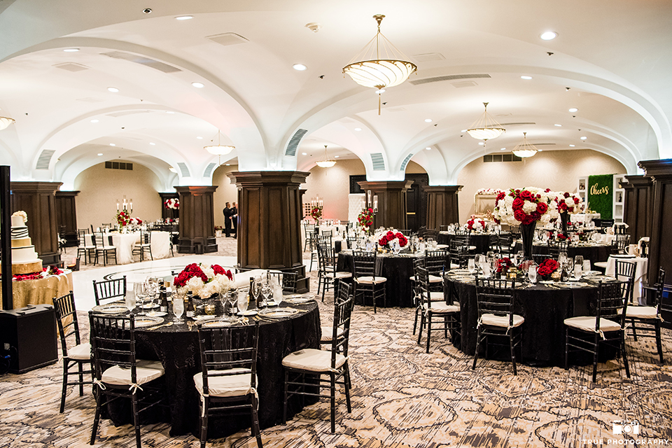 San diego wedding at the us grant hotel wedding reception decor black table linens with black chiavari chairs and white and red flower centerpiece decor with white place settings and gold silverware with candles wedding photo idea for reception table set up