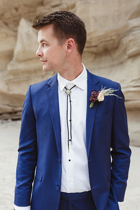 Anza-Borrego-styled-shoot-close-up-on-groom-attire-looking-sideways-groom-in-colbalt-blue-suit-with-chocolate-brown-shoes-and-bolo-tie 