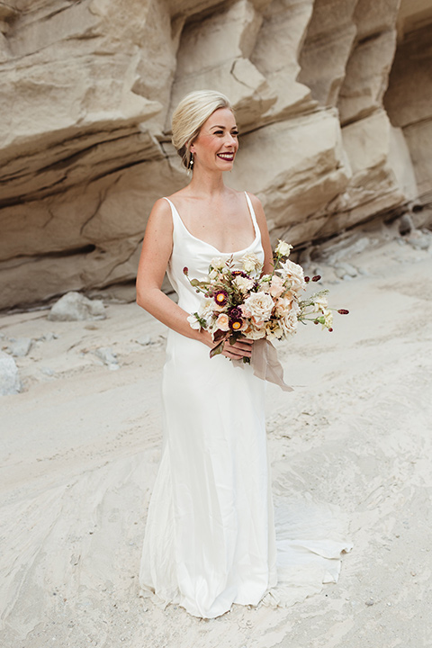 Anza-Borrego-styled-shoot-full-length-bridal-gown-look-bride-in-white-silk-bridal-gown-with-open-back-and-thin-straps-and-hair-in-a-sleek-bun-and-dark-red-lipstick