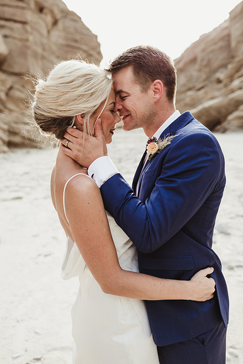  Anza-Borrego-styled-shoot-groom-holding-brides-face-touching-foreheads-bride-in-white-silk-bridal-gown-with-open-back-and-thin-straps-groom-in-colbalt-blue-suit-with-chocolate-brown-shoes-and-bolo-tie