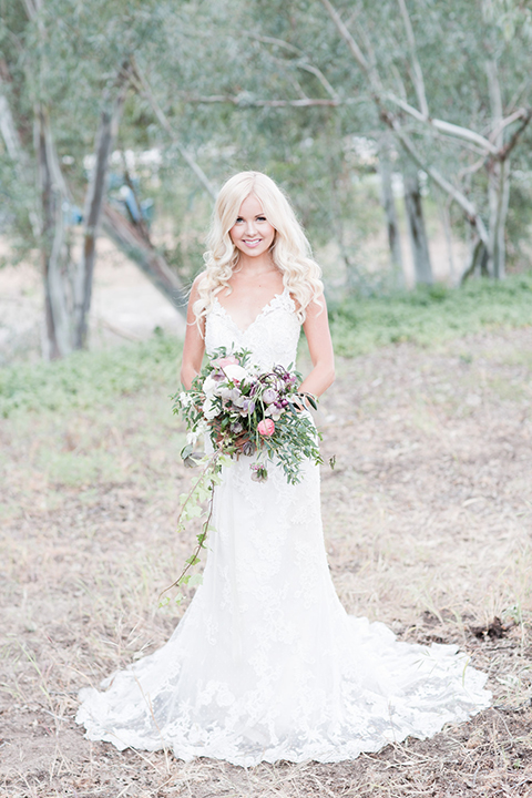 Los angeles outdoor wedding at brookview ranch bride form fitting gown with lace detail on bodice and straps with a plunging neckline holding white and pink floral bridal bouquet