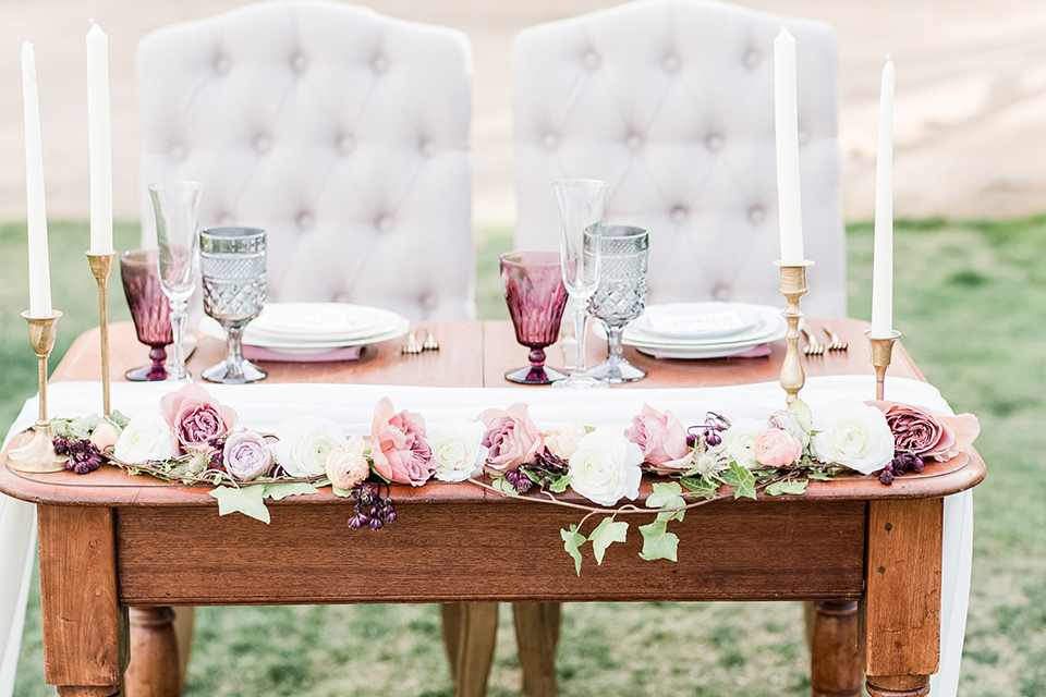 Los angeles outdoor wedding at brookview ranch table set up brown wood table with blush pink napkin decor with white place settings and tall white candles with white vintage chairs and white and pink flower decor