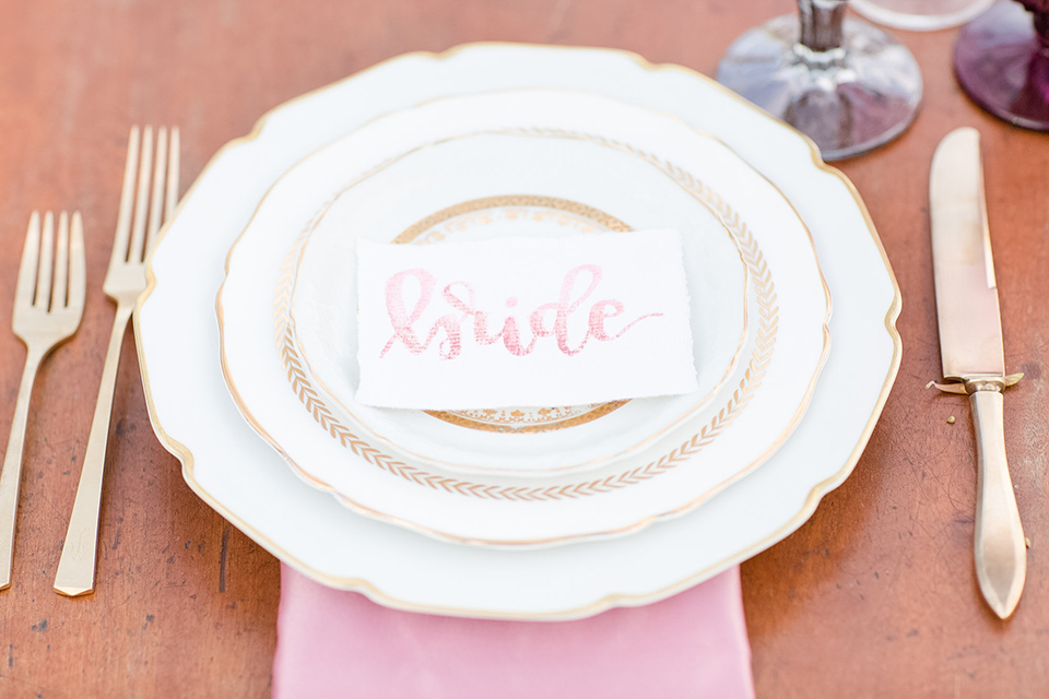 Los angeles outdoor wedding at brookview ranch table set up brown wood table with blush pink napkin decor with white place settings and tall white candles with white vintage chairs and white and pink flower decor