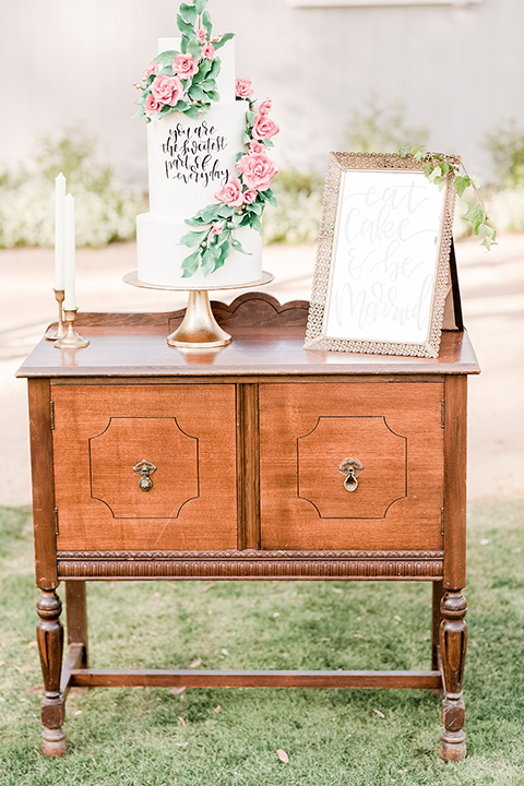 Los angeles outdoor wedding at brookview ranch table set up brown wood table with blush pink napkin decor with white place settings and tall white candles with white vintage chairs and white and pink flower decor