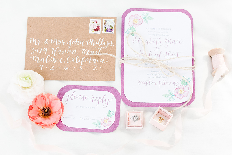 Los angeles outdoor wedding at brookview ranch wedding invitations white invitations with pink border and tan envelope with white calligraphy writing and flower decor on invitations with pink flowers and wedding ring on white background decor wedding photo idea for invitations