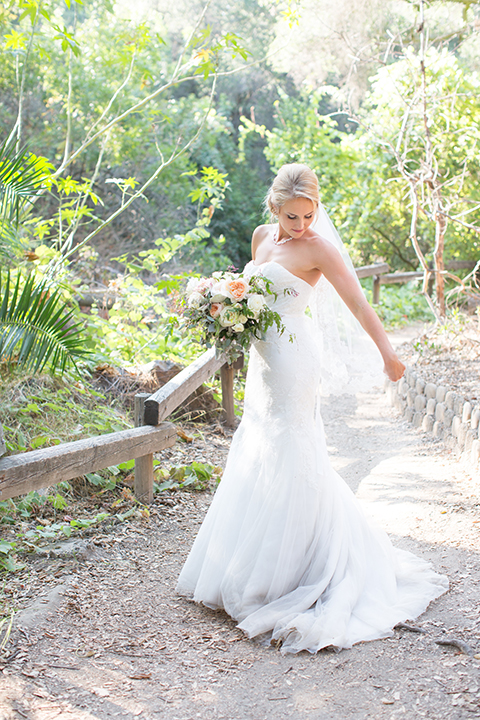 Orange county outdoor wedding at the oak canyon nature center bride form fitting mermaid style strapless gown with a crystal belt and sweetheart neckline with a long veil holding white and green floral bridal bouquet