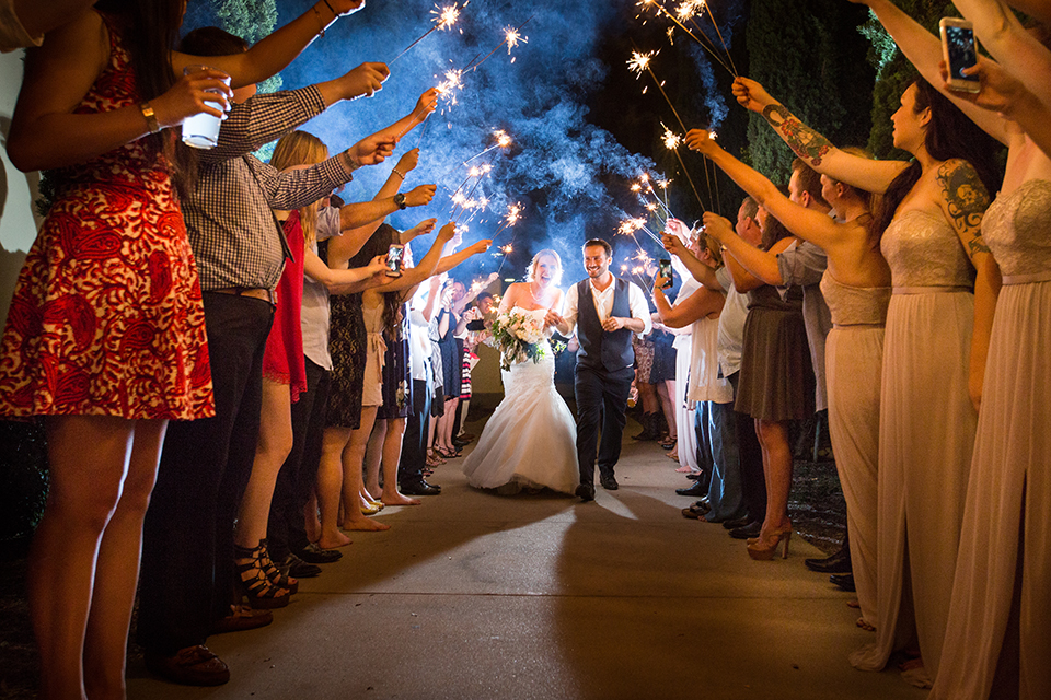 Orange county outdoor wedding at the oak canyon nature center bride form fitting mermaid style strapless gown with a crystal belt and sweetheart neckline with a long veil and groom slate blue notch lapel suit with a matching vest and white dress shirt with a long white tie and white floral boutonniere sparkler exit