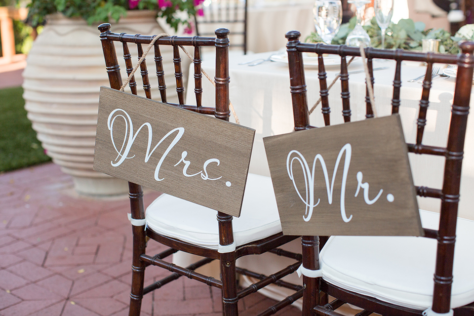 Orange county outdoor wedding at the oak canyon nature center table set up white table linen with white place settings and green and white flower centerpiece decor with dark brown chiavari chairs and candle decor with mr and mrs signs