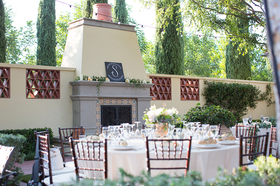 Orange county outdoor wedding at the oak canyon nature center table set up white table linen with white place settings and green and white flower centerpiece decor with dark brown chiavari chairs and candle decor