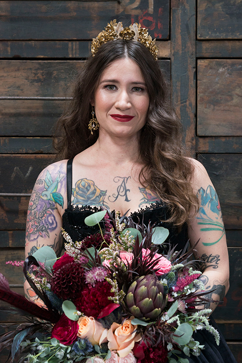Fox and the owl wedding shoot at big daddys antiques bride black ball gown dress with thin spaghetti straps and a sweetheart neckline holding red floral bouquet