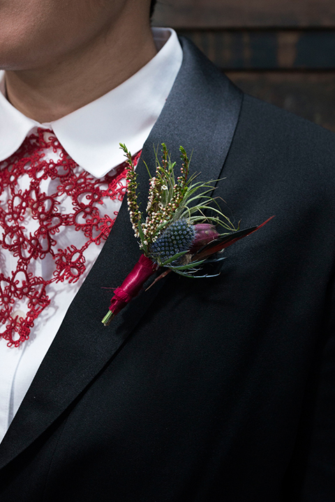 Fox and the owl wedding shot at big daddys antiques bride black womens shawl lapel tuxedo with a white dress shirt and red lace design on neckline with red floral boutonniere