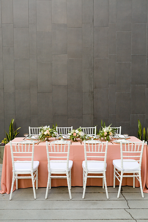 San diego wedding at the hilton bayside table set up with blush pink table linen and white chiavari chairs with white place settings and silver linen napkin decor with short white and green flower centerpiece decor with glassware and silverware