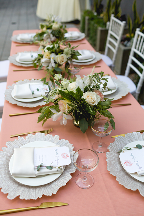 San diego wedding at the hilton bayside table set up with blush pink table linen and white chiavari chairs with white place settings and silver linen napkin decor with short white and green flower centerpiece decor with glassware and silverware