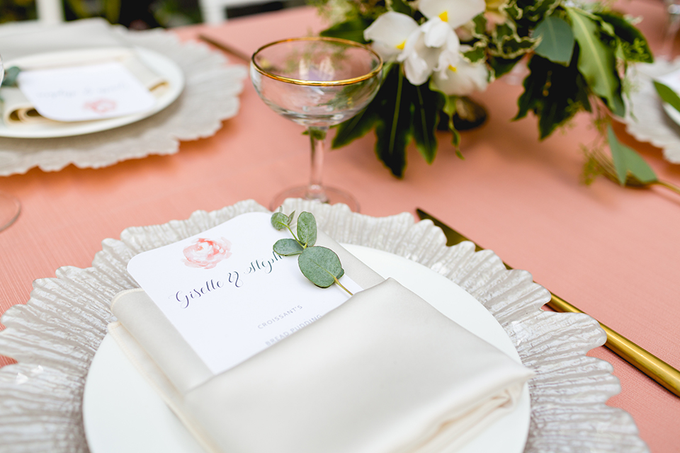 San diego wedding at the hilton bayside table set up with blush pink table linen and white chiavari chairs with white place settings and silver linen napkin decor with short white and green flower centerpiece decor with glassware and silverware