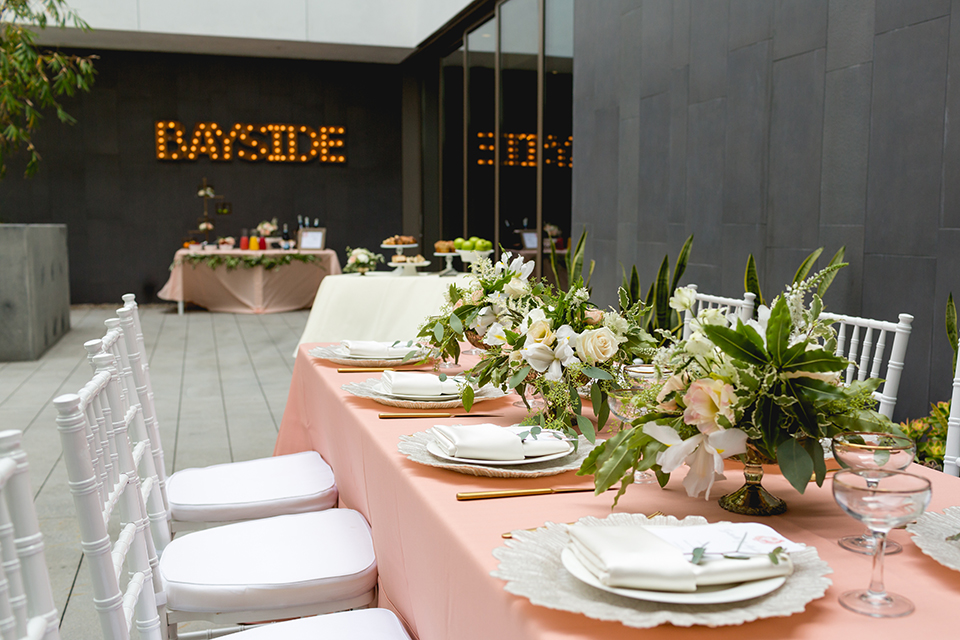 San diego wedding at the hilton bayside table set up with blush pink table linen and white chiavari chairs with white place settings and silver linen napkin decor with short white and green flower centerpiece decor with glassware and silverware