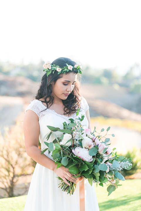 Temecula outdoor wedding at bel vino winery bride a line chiffon gown with straps and lace detail on bodice with a sweetheart neckline and white and green flower crown holding white and green floral bridal bouquet