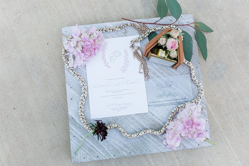 Temecula outdoor wedding at bel vino winery white wedding invitations with grey marble background with pink flowers on edge and greenery decor with jewelry decor wedding photo idea for invitations