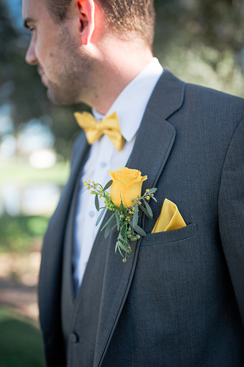 Boutonniere-style-charcoal-grey-notch-lapel-suit-with-a-yellow-bow-tie-and-matching-yellow-floral-boutonniere