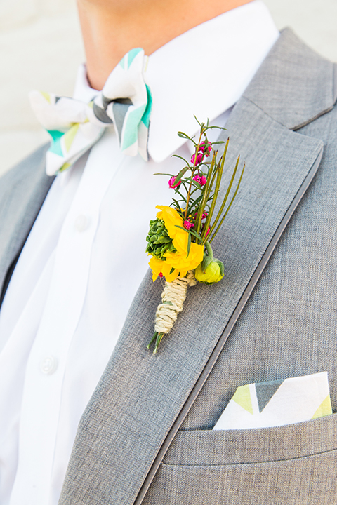 Boutonniere-style-heather-grey-notch-lapel-suit-with-a-colorful-bow-tie-and-yellow-floral-boutonniere