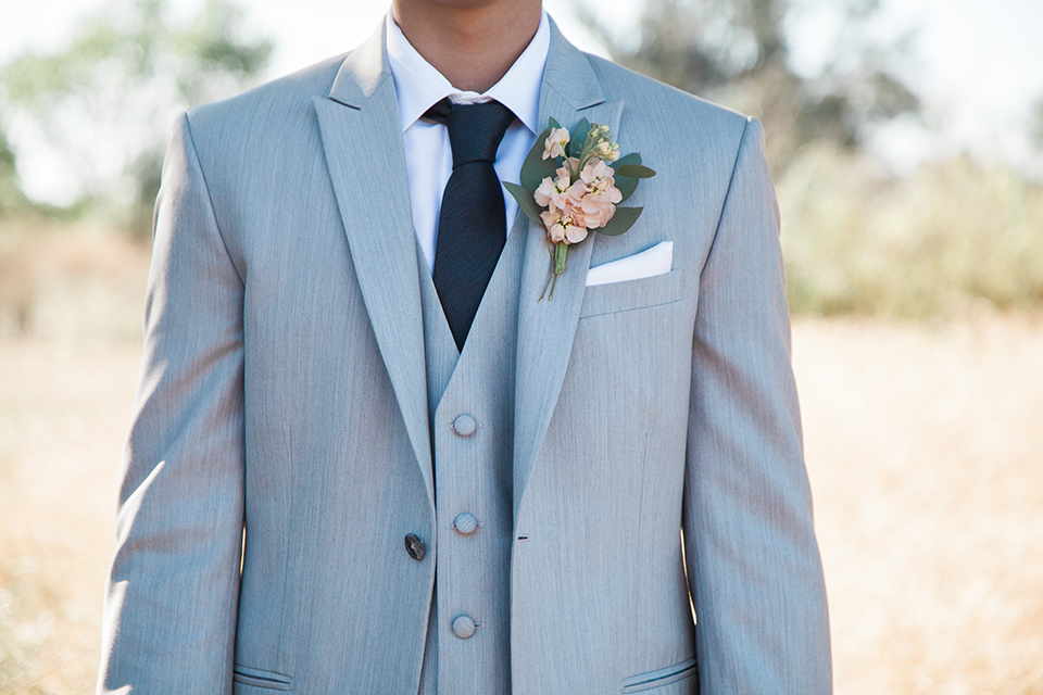 Boutonniere-style-light-grey-peak-lapel-suit-with-a-navy-long-tie-and-light-pink-floral-boutonniere