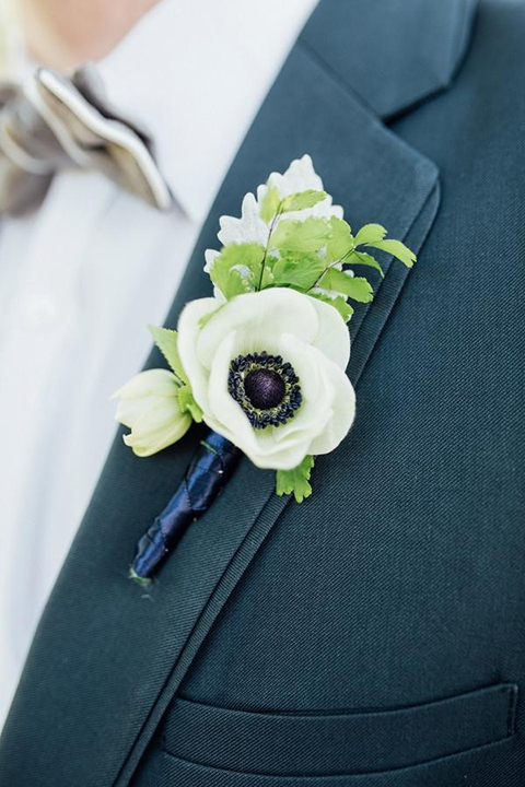 Boutonniere-style-slate-blue-notch-lapel-suit-with-a-grey-pipe-edge-bow-tie-and-simple-white-floral-boutonniere