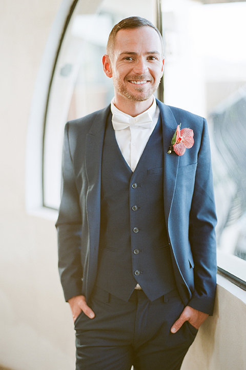 Los angeles same sex outdoor wedding at malibu solstice canyon groom blue notch lapel suit with a white dress shirt and white bow tie with an orange floral boutonniere