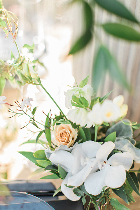 Los angeles same sex wedding at malibu solstice canyon table set up light brown wood table with white chairs and white and green flower centerpiece decor with white candles in glass vases and clear glass plates wedding photo idea close up