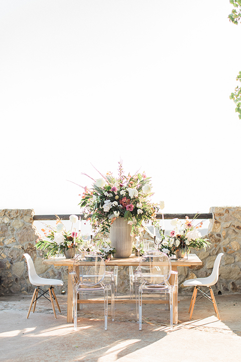 Los angeles same sex wedding at malibu solstice canyon table set up light brown wood table with white chairs and white and green flower centerpiece decor with white candles in glass vases and clear glass plates wedding photo idea side view