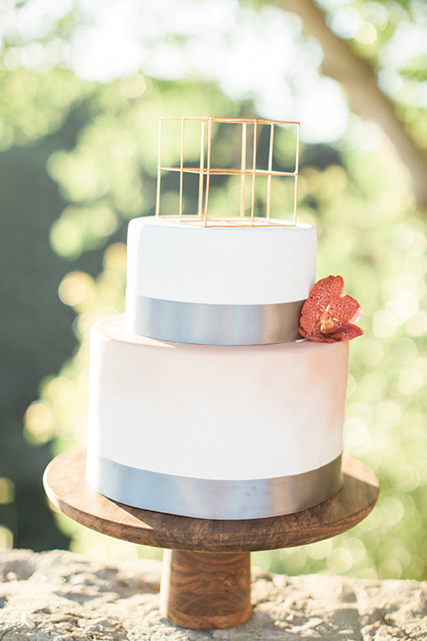 Los angeles same sex wedding at malibu solstice canyon table set up light brown wood table with white chairs and white and green flower centerpiece decor with white candles in glass vases and clear glass plates wedding photo idea with wedding cake two tier white cake with grey lining