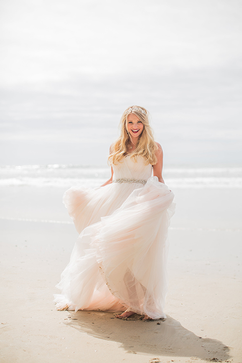 San diego beach wedding at blacks beach bride strapless ball gown with a sweetheart neckline and crystal belt and headband holding dress and walking on the beach