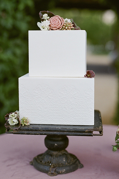 Santa barbara outdoor black tie wedding at kestrel park two tier white wedding cake square shaped on black cake tray with greenery floral decor on bottom and on top with dusty pink linen decor on table wedding photo idea for cake