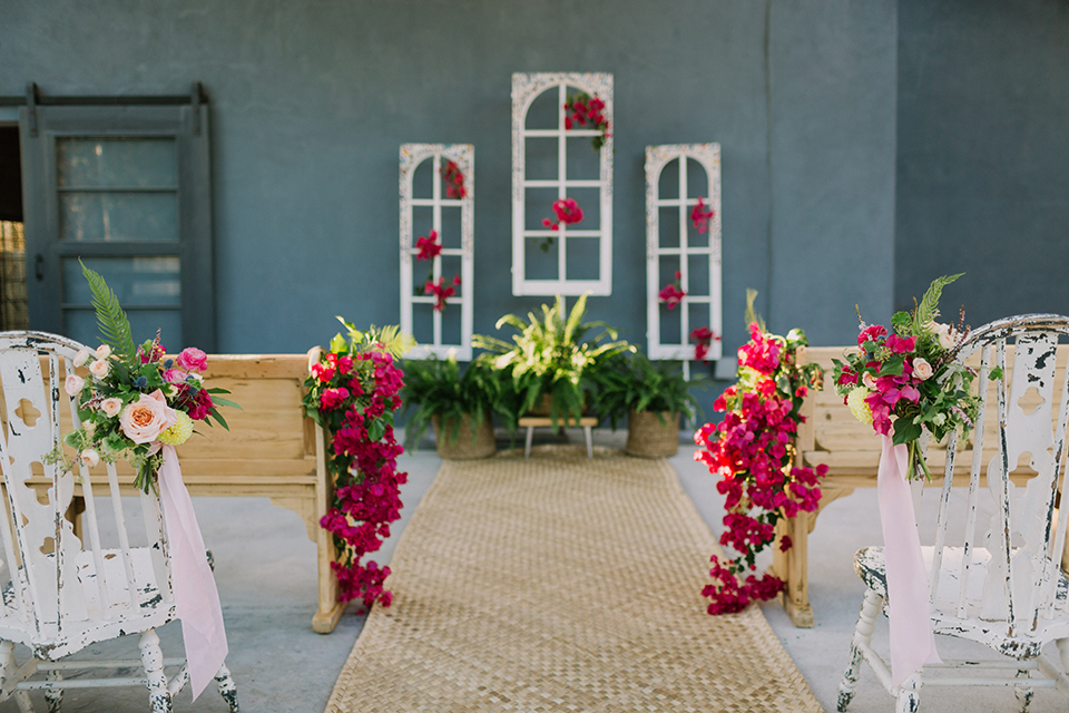 Los angeles outdoor colorful wedding at city libre ceremony set up with light brown wood aisle and wooden benches with white chairs and bright pink florals and white window pane decor on wall wedding photo idea for ceremony set up