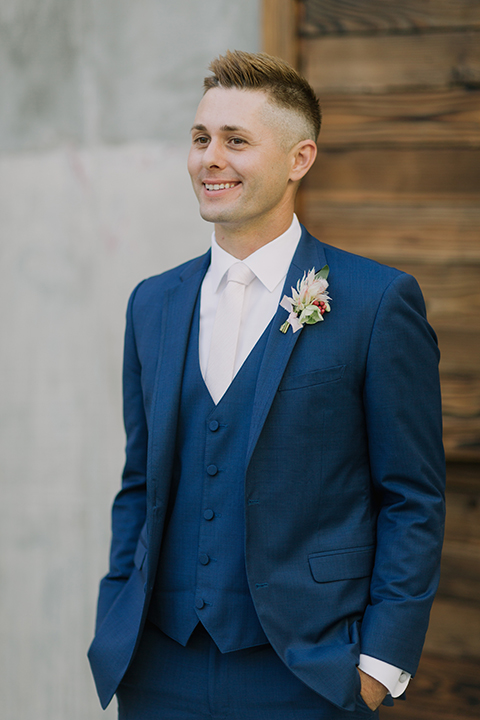 Los angeles outdoor colorful wedding at city libre groom cobalt blue notch lapel suit by allure men with a matching vest and a white dress shirt with a long white matte tie and white floral boutonniere standing with hands in pockets close up