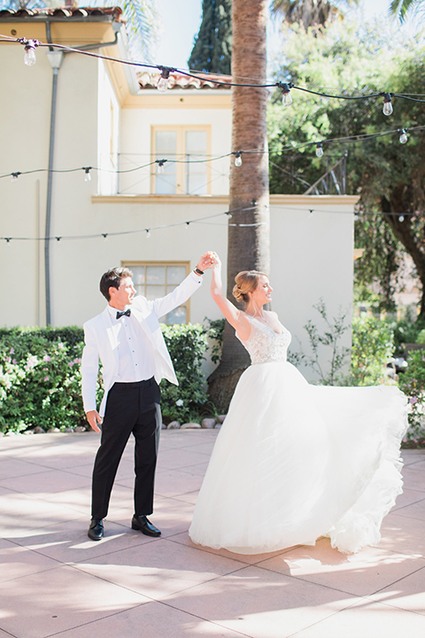 Pasadena outdoor wedding at the maxwell house bride mermaid style gown with thin spaghetti straps and beaded detail with a sweetheart neckline and groom white dinner jacket with black tuxedo pants and a white dress shirt with a black bow tie dancing and twirling bride