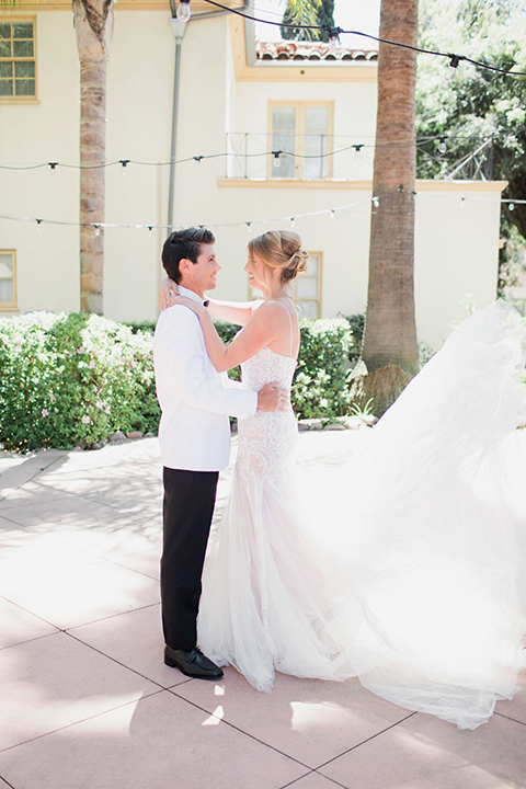 Pasadena outdoor wedding at the maxwell house bride mermaid style gown with thin spaghetti straps and beaded detail with a sweetheart neckline and groom white dinner jacket with black tuxedo pants and a white dress shirt with a black bow tie hugging and smiling