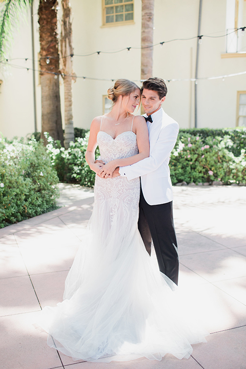 Pasadena outdoor wedding at the maxwell house bride mermaid style gown with thin spaghetti straps and beaded detail with a sweetheart neckline and groom white dinner jacket with black tuxedo pants and a white dress shirt with a black bow tie hugging