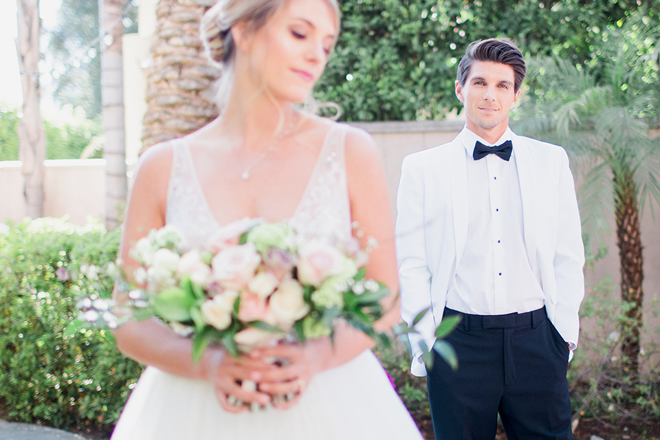 Pasadena outdoor wedding at the maxwell house bride mermaid style gown with thin spaghetti straps and beaded detail with a sweetheart neckline and groom white dinner jacket with black tuxedo pants and a white dress shirt with a black bow tie standing smiling