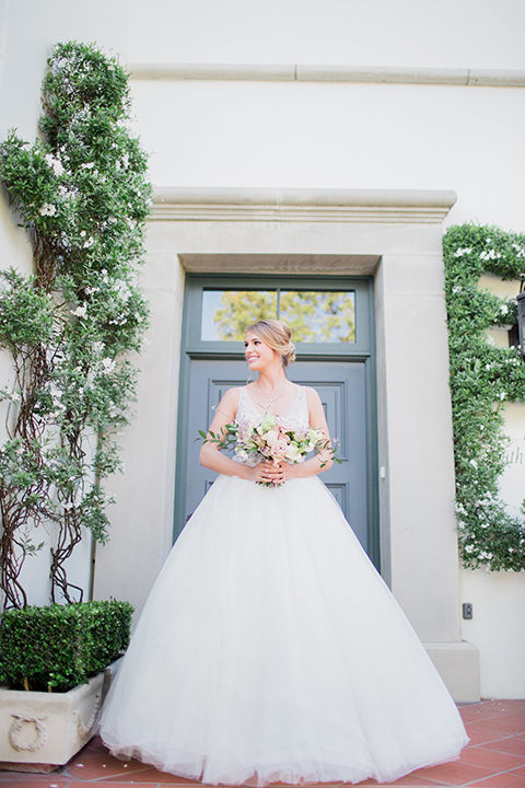 Pasadena outdoor wedding at the maxwell house bride ball gown with straps and a plunging neckline with beaded detail holding white and green floral bridal bouquet