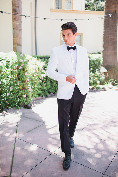 Pasadena outdoor wedding at the maxwell house groom white dinner jacket with black tuxedo pants and a white dress shirt with a black bow tie holding jacket