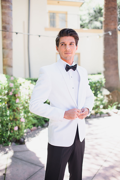 Pasadena outdoor wedding at the maxwell house groom white dinner jacket with black tuxedo pants and a white dress shirt with a black bow tie buttoning jacket