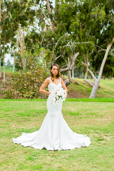 Southern california outdoor wedding at diamond bar golf course bride form fitting mermaid style gown with silver beaded straps and a sweetheart neckline with a low back design and beaded detail with white and green floral bridal bouquet 