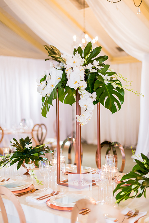 Southern california outdoor wedding at diamond bar golf course table set up white table with greenery floral decor and rose gold chairs with hanging decor and wall with greenery florals and white and gold place settings with gold silverware