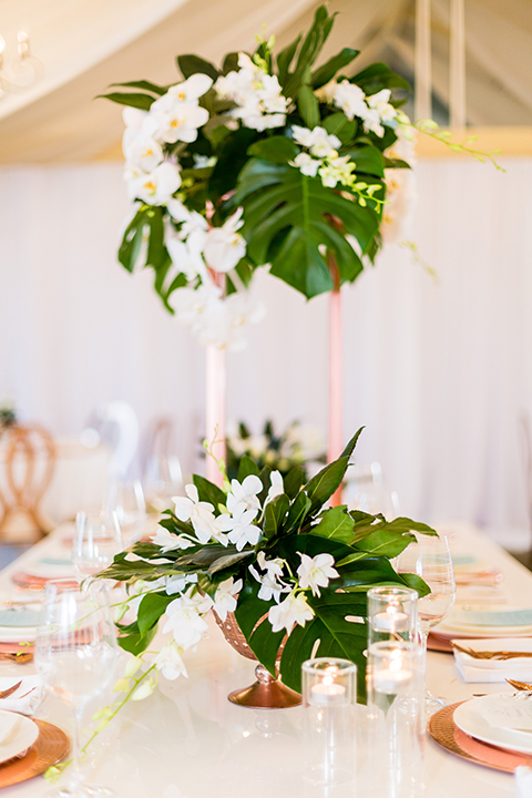 Southern california outdoor wedding at diamond bar golf course table set up white table with greenery floral decor and rose gold chairs with hanging decor and wall with greenery florals and white and gold place settings with gold silverware