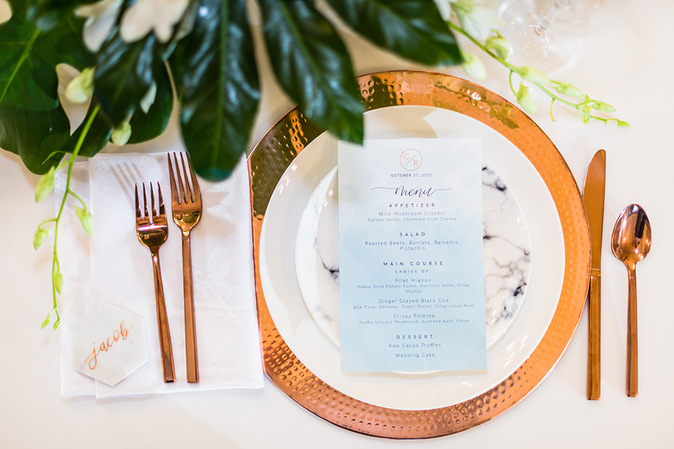 Southern california outdoor wedding at diamond bar golf course table set up white table with greenery floral decor and rose gold chairs with hanging decor and wall with greenery florals and white and gold place settings with gold silverware