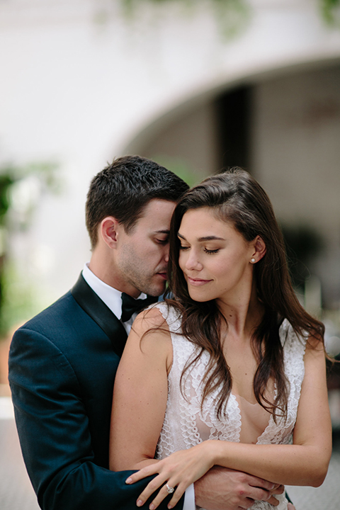 Southern-california-wedding-at-the-ebell-of-long-beach-bride-and-groom-dancing-and-hugging-bride-wearing-a-lace-a-line-dress-with-straps-and-hair-in-loose-down-waves-and-groom-in-navy-tux-with-black-trim-and-black-bowtie